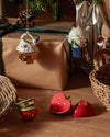 Unique Christmas ornaments by Alessi, featuring a swan, pearl globe, and heart, displayed with wrapped gifts.