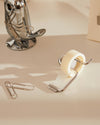 Filo tape dispenser with a chrome wire frame and cream tape by Alessi, angled on a desk next to paper clips and a chrome fish holder.