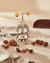 Silver and gold strongman nutcracker by Alessi, featuring a striped shirt, golden dumbbells, and a red and white circus tent base.