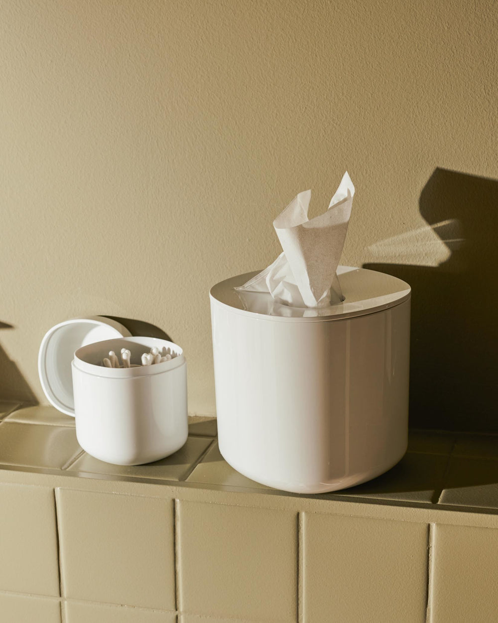 White Birillo tissue box by Alessi, with a rounded design, alongside a matching cotton swab holder.