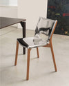 Modern clear chrome-effect chair with natural wood legs by Alessi, positioned at an angle in a contemporary room.