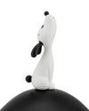 White and black stylized dog figure by Alessi, sitting with its head tilted up, on a curved black base.