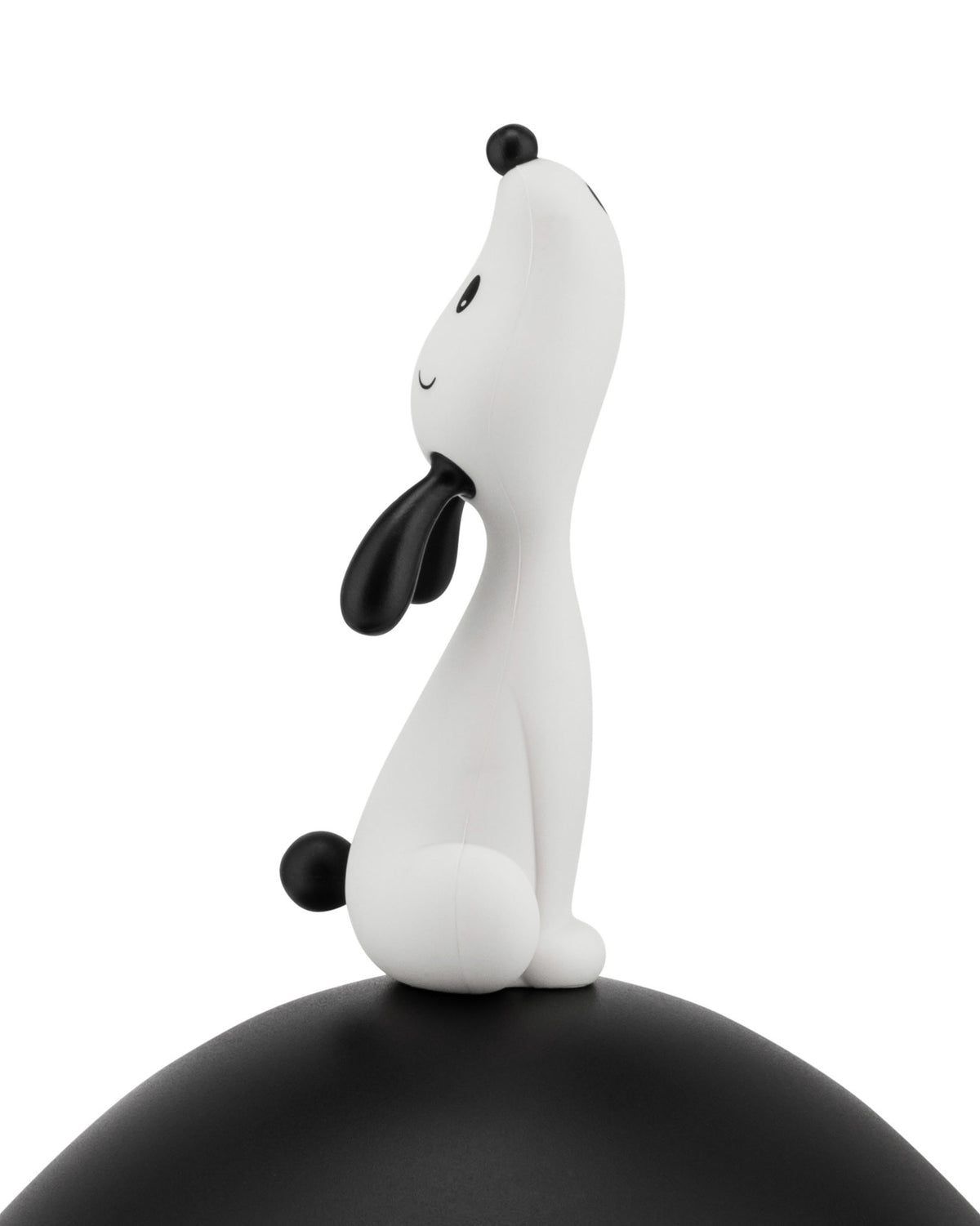 White and black stylized dog figure by Alessi, sitting with its head tilted up, on a curved black base.