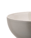 Warm grey ceramic bowl by Alessi featuring a glossy off-white interior and textured matte exterior, cropped side view.