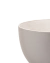 Light grey ceramic bowl by Alessi with a matte exterior and glossy inner rim, cropped side view.