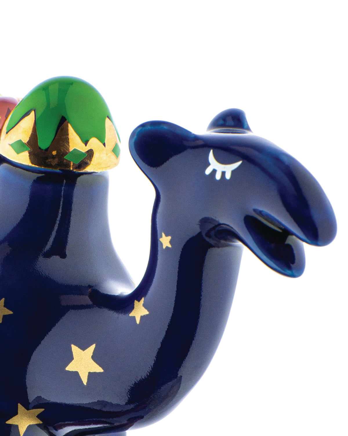 A navy blue decorative camel by Alessi with gold stars, a green and gold patterned hump, and a stylized closed eye.