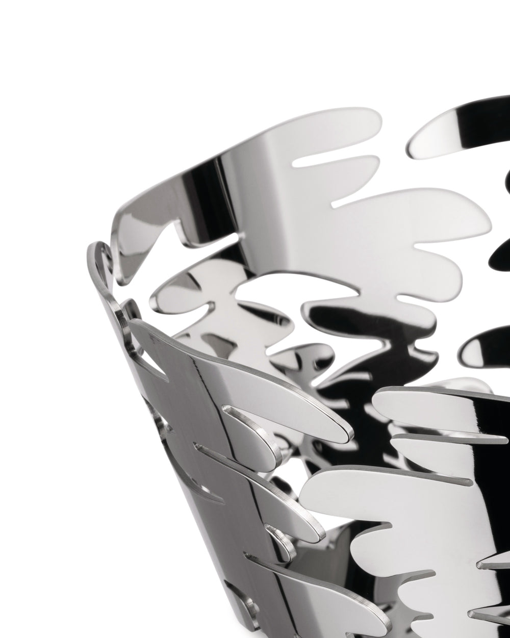 Silver metal basket by Alessi with intricate leaf-like cut-out patterns, in a cropped close-up.