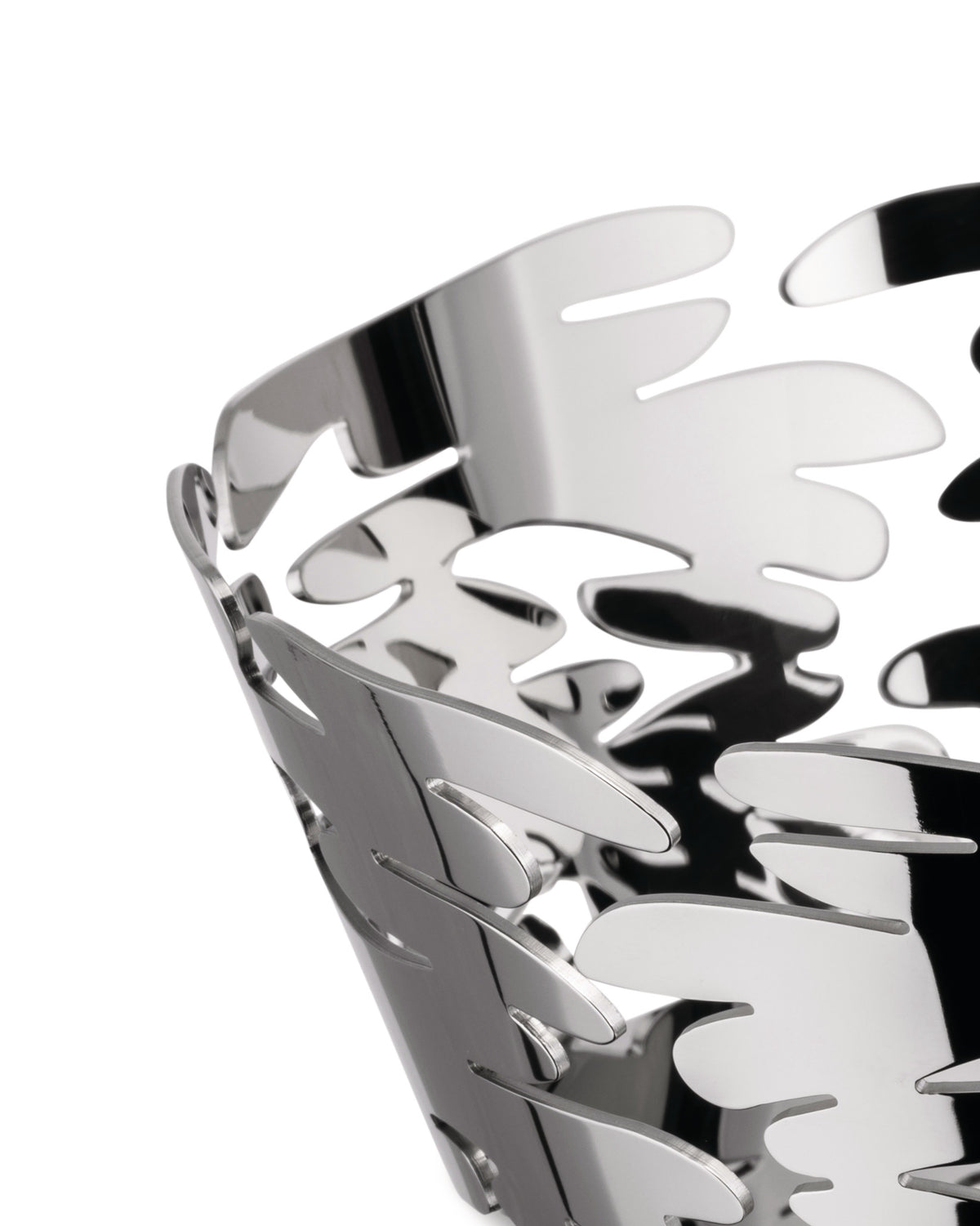 Silver metal basket by Alessi with intricate leaf-like cut-out patterns, in a cropped close-up.