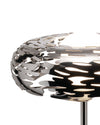 Polished silver metal lamp by Alessi with an intricate laser-cut bark-like pattern, illuminated from within.