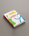 A white hardcover book titled 'La Fabbrica dei Sogni' by Alessi, with yellow, green, and blue kitchenware illustrations, displayed at an angle on a grey surface.