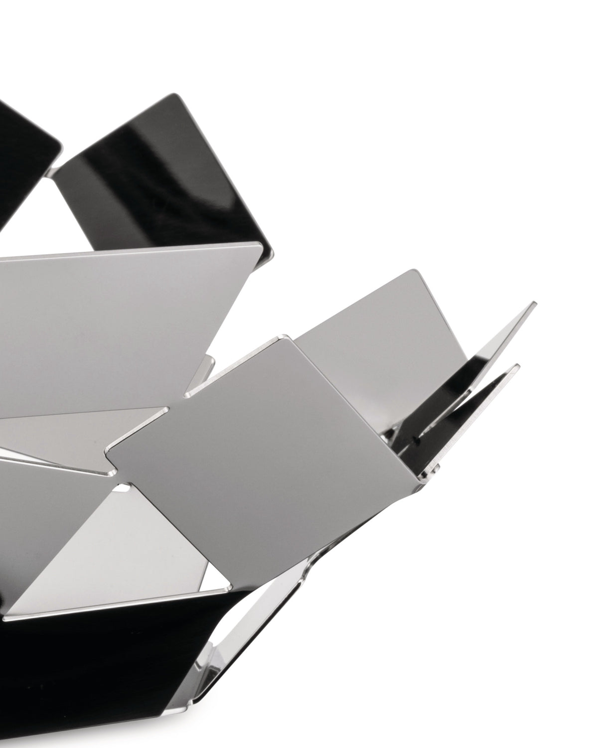 Silver geometric metal fruit bowl by Alessi, featuring an open, abstract design of interlocking reflective panels.