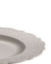 Light gray plate by Alessi featuring a scalloped edge and embossed scrollwork on the rim.