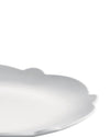 White scalloped serving platter by Alessi, with a matte finish, in a cropped, angled view.