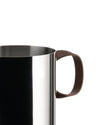 Polished stainless steel pot by Alessi with a brown leather handle and a brushed rim, close-up side view.