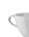 White ceramic cup by Alessi, visible from the side with a prominent curved handle.