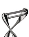 Silver metallic peeler by Alessi with a unique twisted handle and serrated blade, close-up.