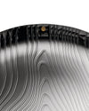 Dark metallic veneer by Alessi with wavy, ridged contours and a glossy finish.