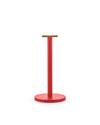 Red metal paper towel holder by Alessi with a round wooden top, cylindrical post, and round base.