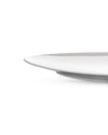 White ceramic dinner plate by Alessi, with a shallow profile and subtle raised edge, cropped view.