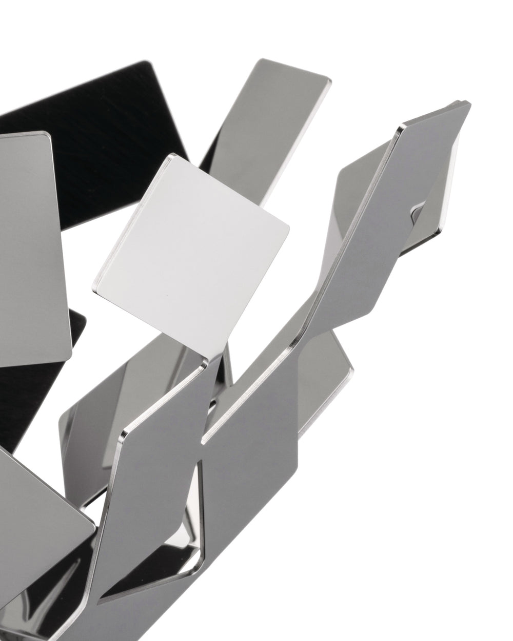 Metallic geometric fruit bowl by Alessi, composed of angled, reflective silver and dark panels on white.
