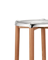 Silver metallic stool with light brown wooden legs by Alessi, featuring a contoured seat, cropped view.