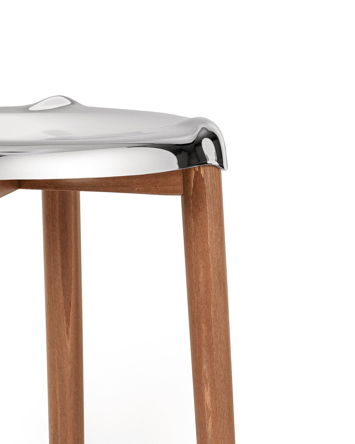 Chrome-finished seat by Alessi with light brown wooden legs, in a close-up view.