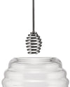 Clear glass honey pot by Alessi with a shiny silver metal spiral dipper dripping honey.