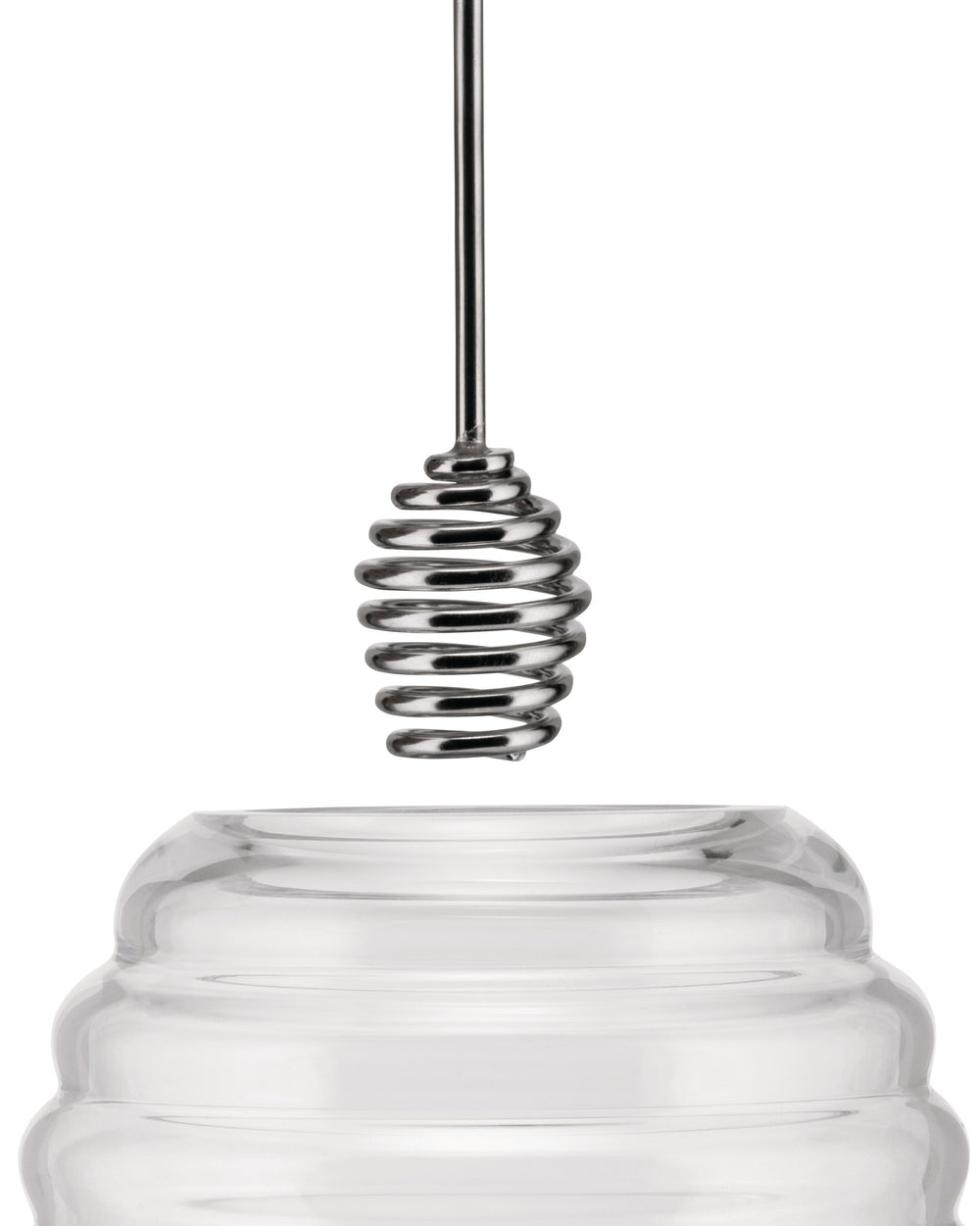 Clear glass honey pot by Alessi with a shiny silver metal spiral dipper dripping honey.