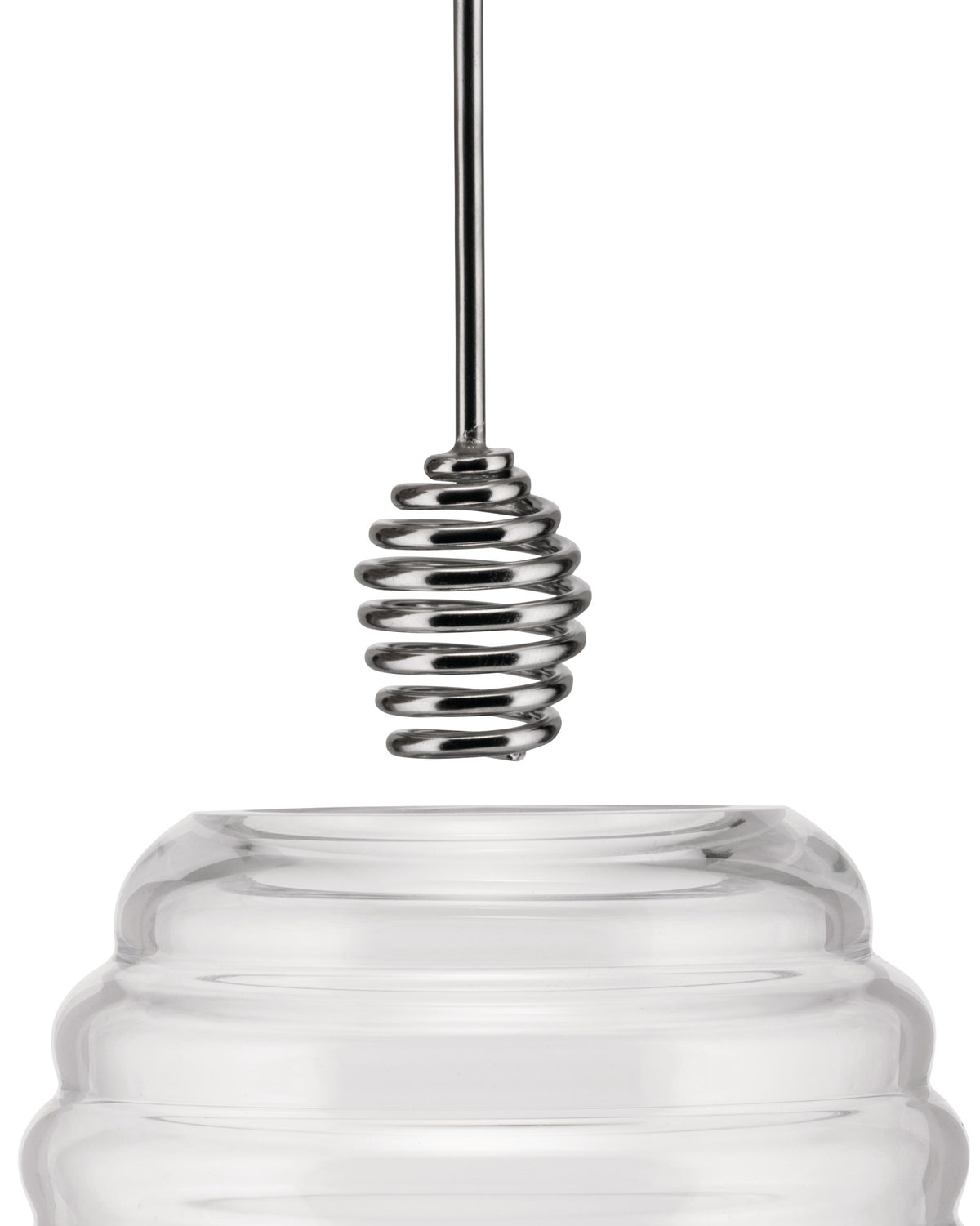 Clear glass honey pot by Alessi with a shiny silver metal spiral dipper dripping honey.