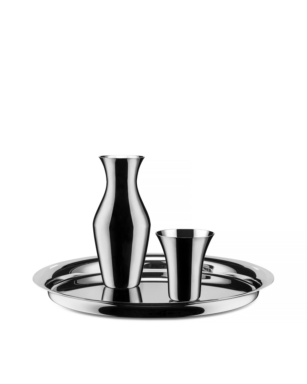 Shiny round metal tray by Alessi, holding a matching reflective pitcher and cup.