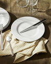 Sleek stainless steel Santiago cutlery by Alessi, featuring a knife, fork, and spoon on a white plate.