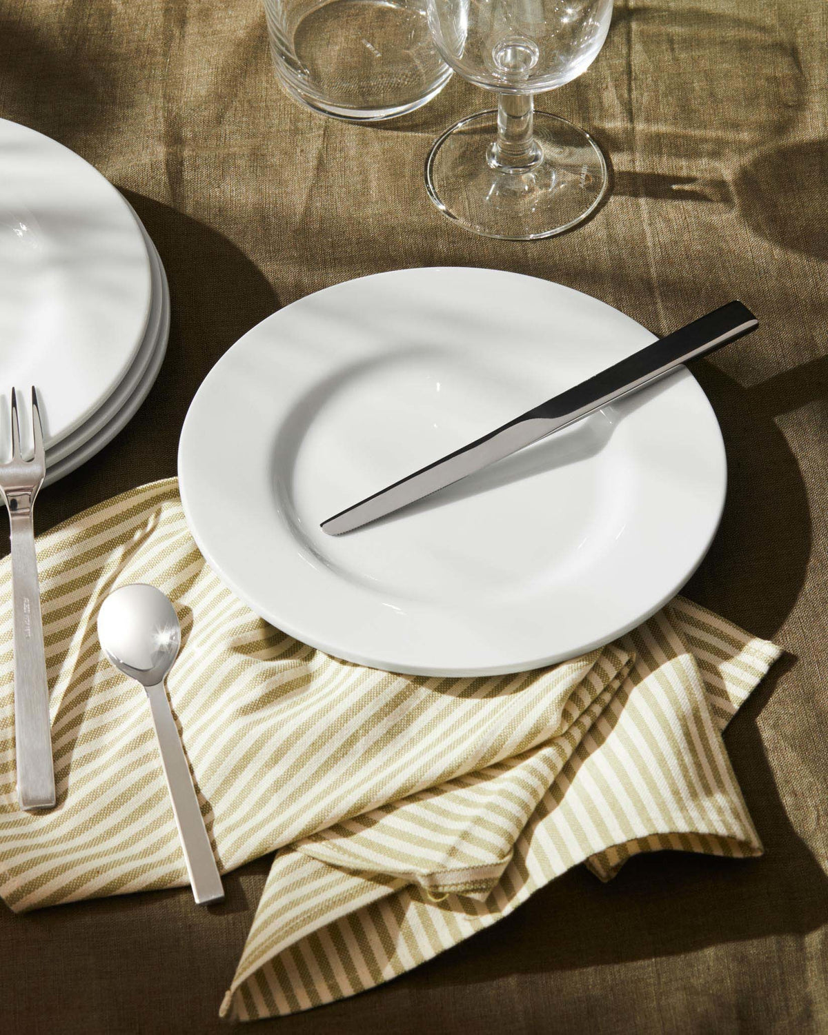 Sleek stainless steel Santiago cutlery by Alessi, featuring a knife, fork, and spoon on a white plate.
