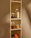 Brown veneer by Alessi on a cabinet panel with a subtle vertical grain texture, next to open kitchen shelves.