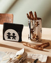Silver metal Girotondo container by Alessi, featuring cutout figures and filled with breadsticks.