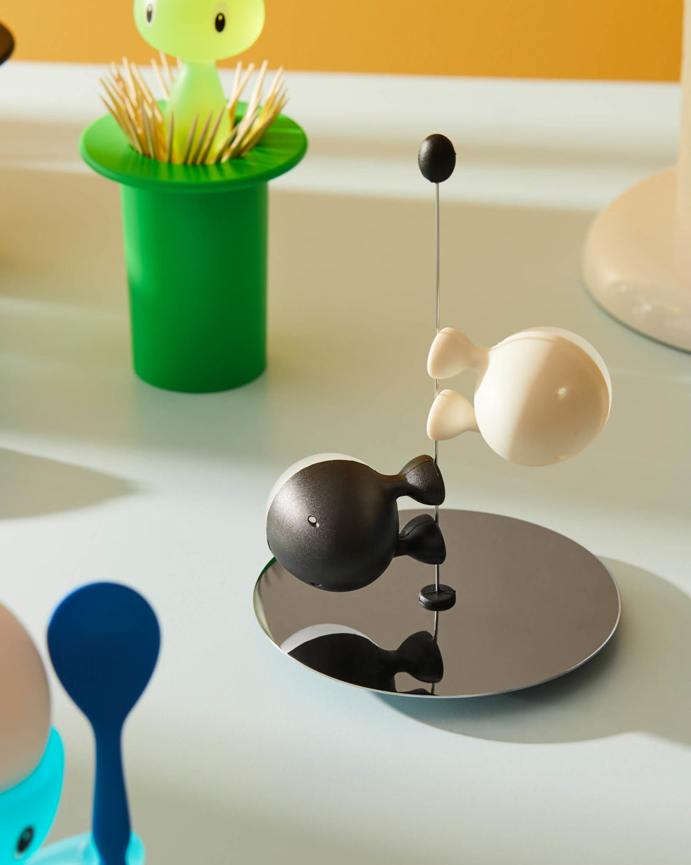Black and white magnetic fish-shaped Lilliput salt and pepper shakers by Alessi on a mirrored base.