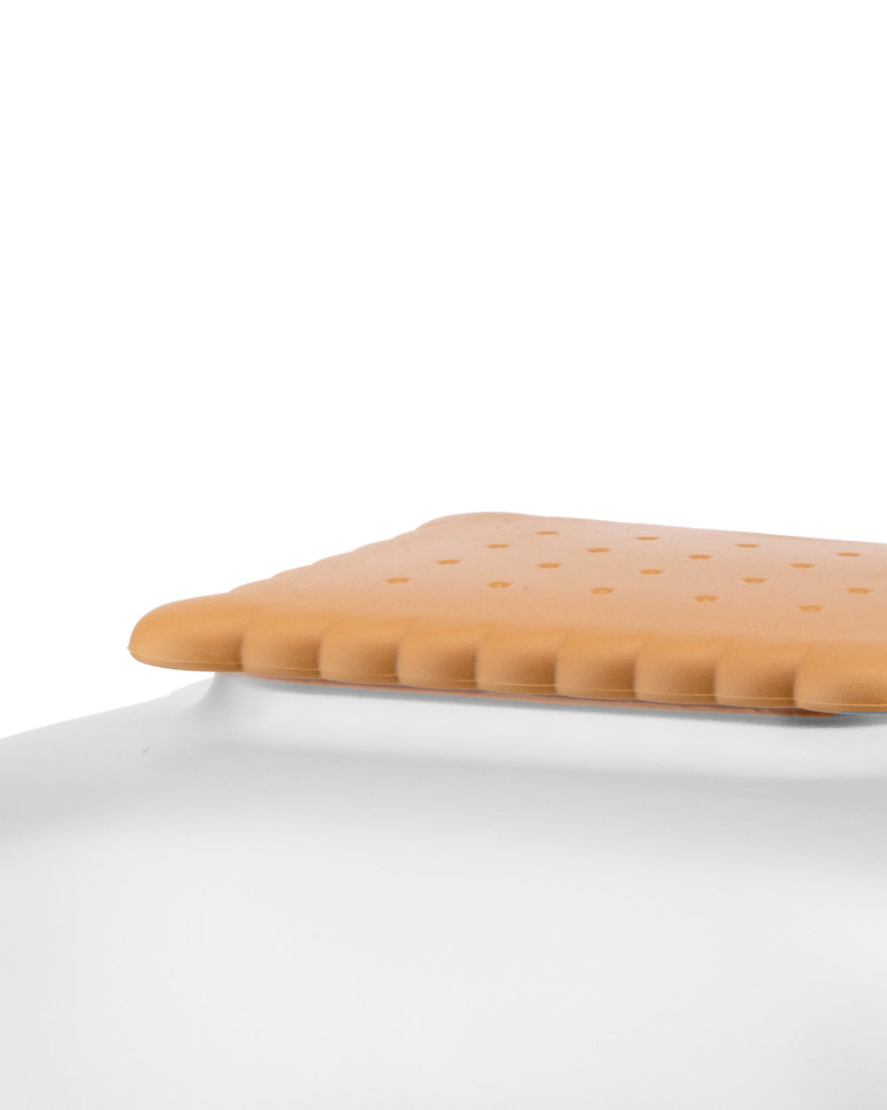 Light brown rectangular biscuit box by Alessi, with ridged sides and a dimpled top, viewed from a close-up angle.