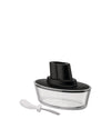 Clear glass and black Ship-shaped butter dish by Alessi, shown with a white-handled spreader.