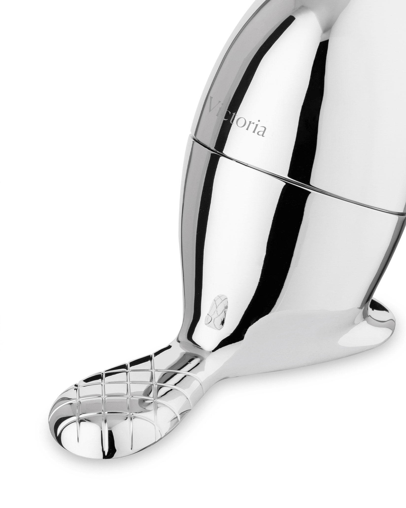 Angled view of a chrome-plated beaver-shaped object by Alessi, featuring 'Victoria' text, a shoe icon, and a grid-patterned tail.
