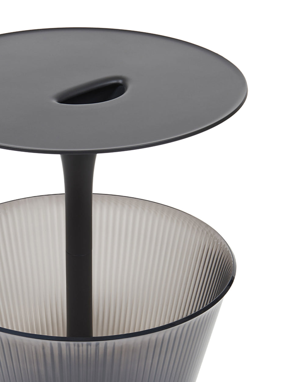 Dark grey lidded container by Alessi with an oval handle indentation and a translucent ribbed body.