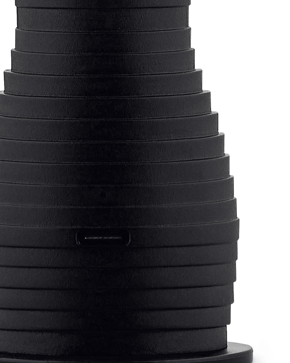 Black, stacked espresso maker by Alessi, with tapered form, textured horizontal ridges, and visible USB-C port.