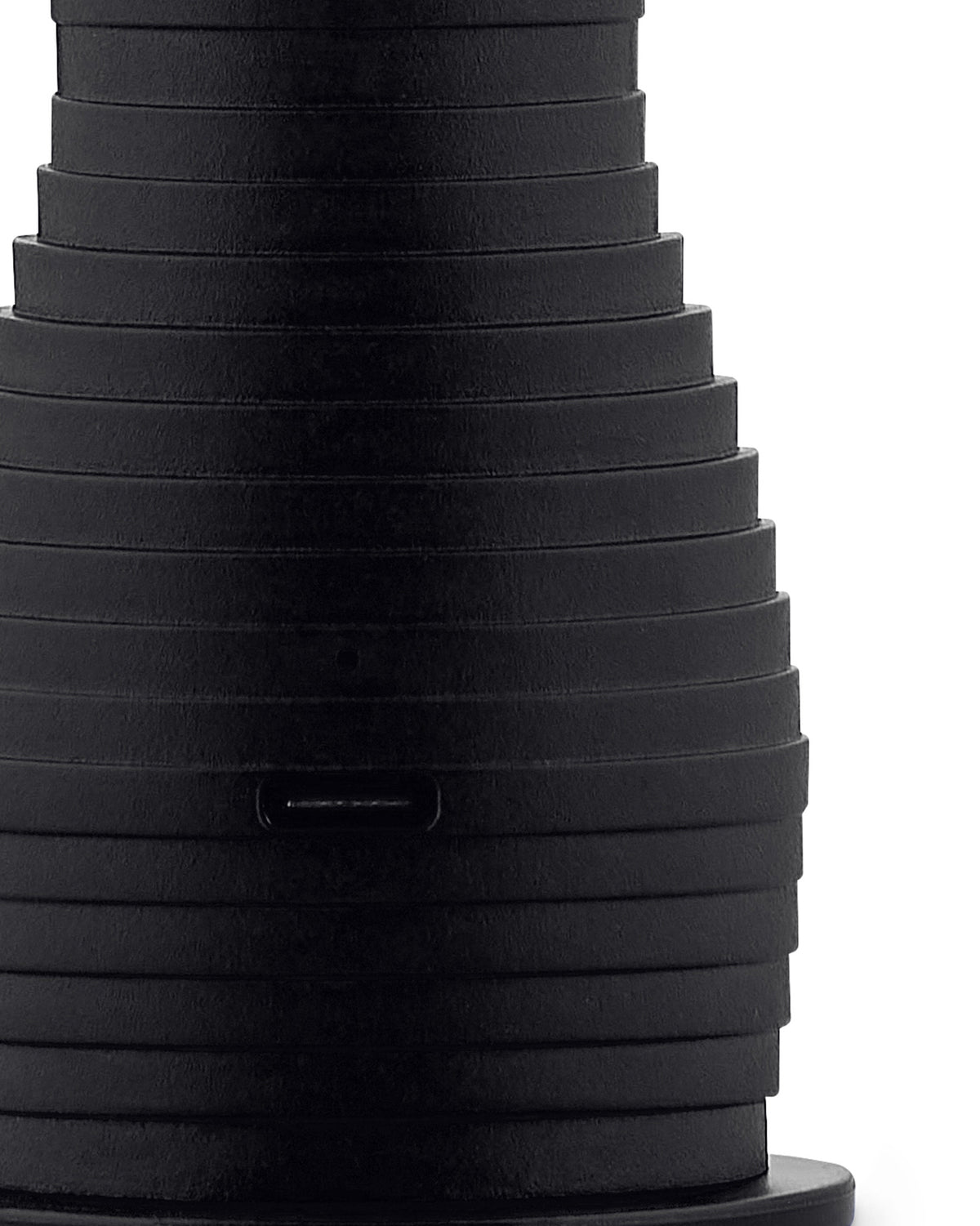Black, stacked espresso maker by Alessi, with tapered form, textured horizontal ridges, and visible USB-C port.
