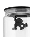 Clear glass storage jar by Alessi featuring a black 'Gianni' figure hanging inside from the lid.
