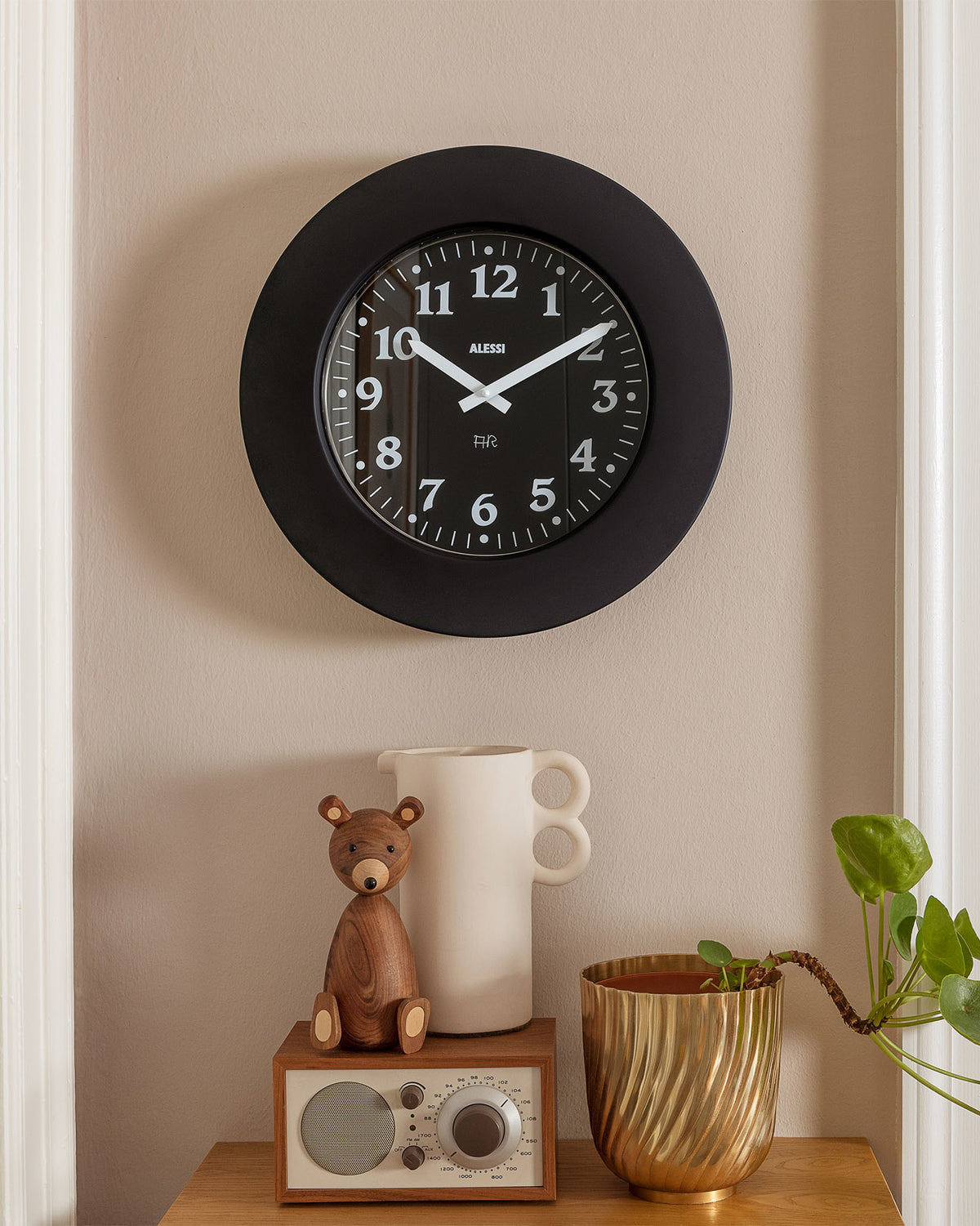 Black round wall clock by Alessi with white numbers, minute markers, and hands, featuring 'HR' and 'ALESSI' text.