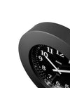 Black clock by Alessi with white numbers and hands, angled close-up view showing "FR" inscription.