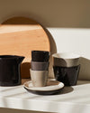 Ceramic Tonale tableware collection by Alessi, featuring stacked cups and plates in neutral shades.