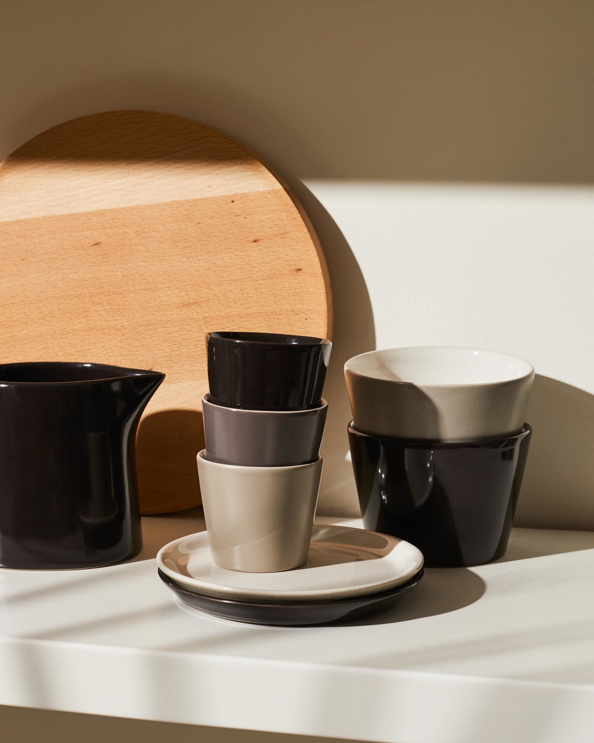 Ceramic Tonale tableware collection by Alessi, featuring stacked cups and plates in neutral shades.