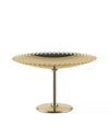 Gold fruit holder by Alessi with a scalloped edge, elevated on a polished stem and base.
