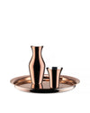 Polished copper pitcher by Alessi, accompanied by a tapered cup on a round tray.