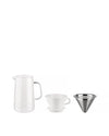 Slow coffee brewing set by Alessi featuring a clear glass carafe, white ceramic dripper, and stainless steel filter arranged side-by-side.