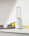 White pleated blender by Alessi with clear bottle, shown on a marble countertop with fruit and milk.
